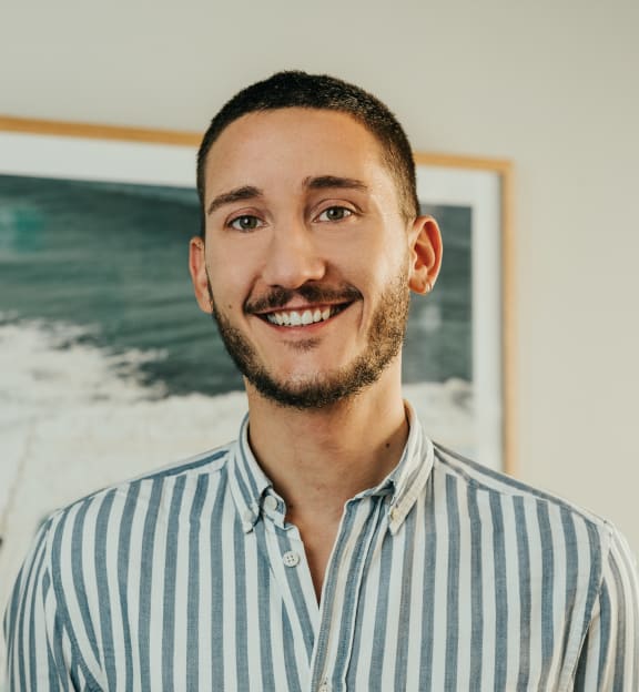 a man in a striped shirt standing in front of a painting