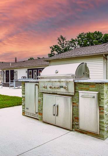 A backyard with a white fence and a stone and wood outdoor kitchen.