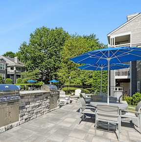 A patio with a stone wall and a blue umbrella.