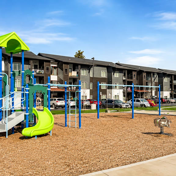 A playground with a green and blue slide and a yellow canopy.