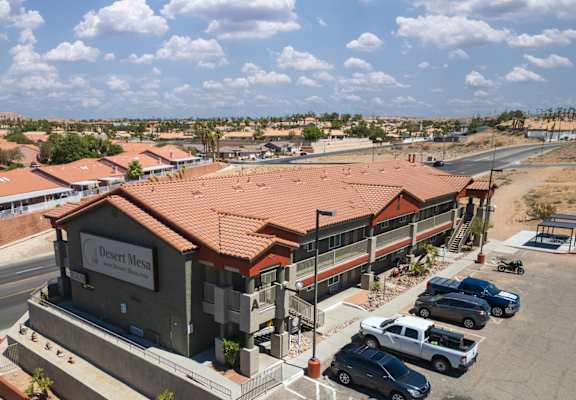 A building with the sign "Desert Mess" is surrounded by parked cars.
