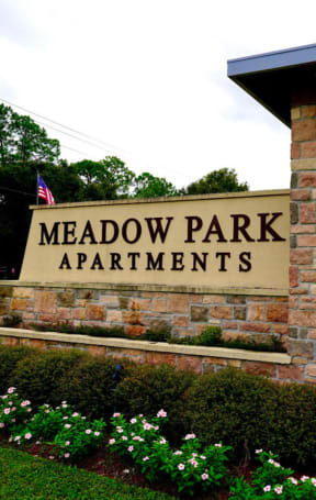 a stone monument with a sign that says meadow park apartments