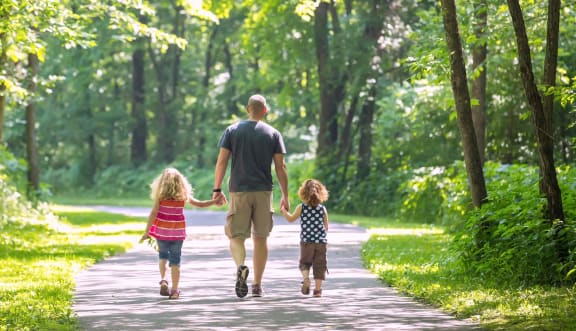 a man and two children walking down a path in the woods at Foxtail Hollow, Blaine Minnesota