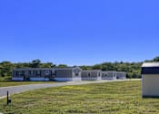 Thumbnail 6 of 6 - A sunny day at a grassy field with a building and a car in the foreground.