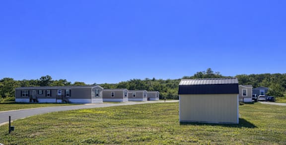 A sunny day at a grassy field with a building and a car in the foreground.