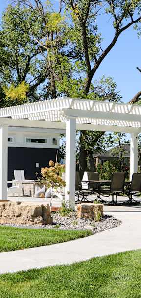 A white gazebo is surrounded by a grassy area and trees.