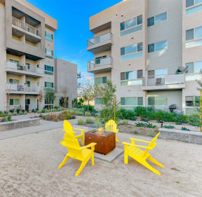 an outdoor area with yellow chairs and a suitcase in front of an apartment building