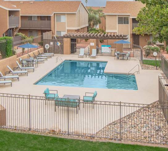 A swimming pool surrounded by a fence and chairs.