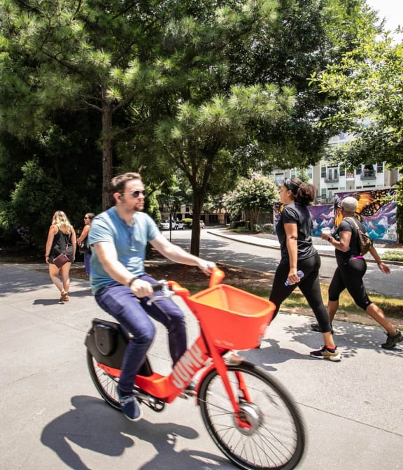 Man riding bike on The Atlanta Beltline, adults in background excersing and walking on beltine in Atlanta, GA