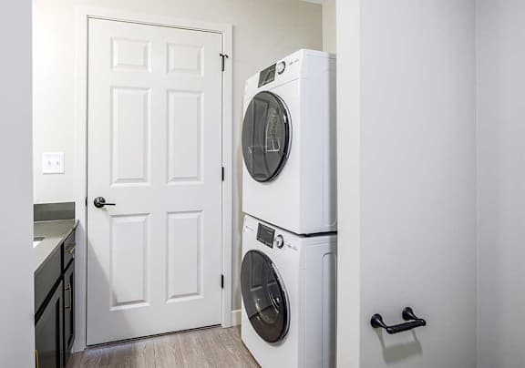 a stacked washer and dryer across from the bathroom vanity sink
