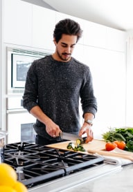 A man is chopping vegetables on a cutting board in a kitchen. at The Retreat, Sumner, WA, 98390
