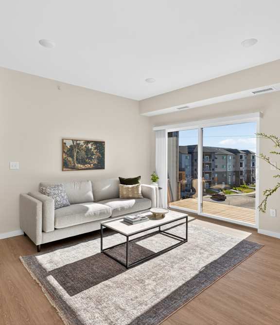 A living room with a couch, a coffee table, and a large window.