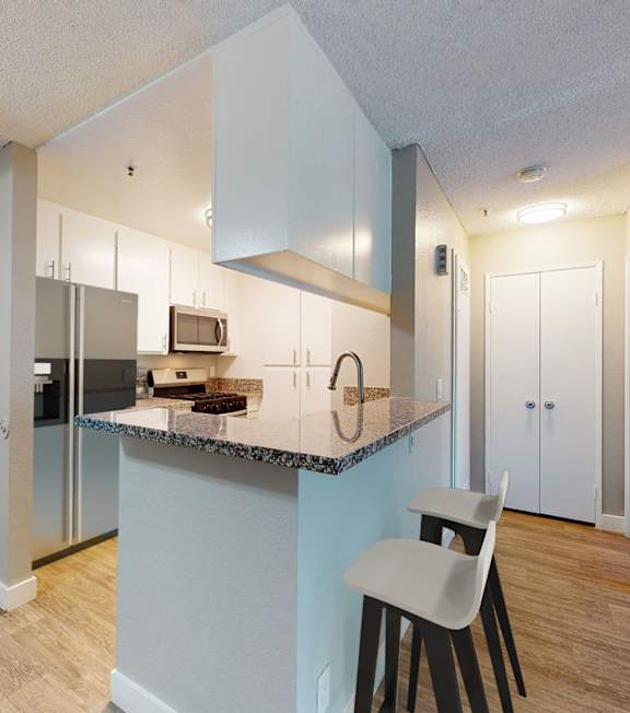 A kitchen with a white chair and a counter with a sink.