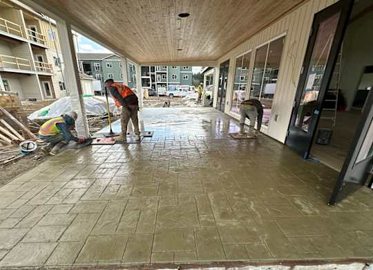 Workers installing stamped concrete covered walkway at The Elowen apartment construction site in Lacey WA.