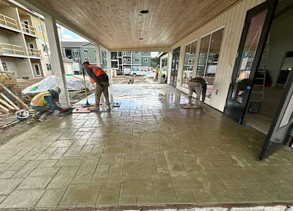 Workers installing stamped concrete covered walkway at The Elowen apartment construction site in Lacey WA.
