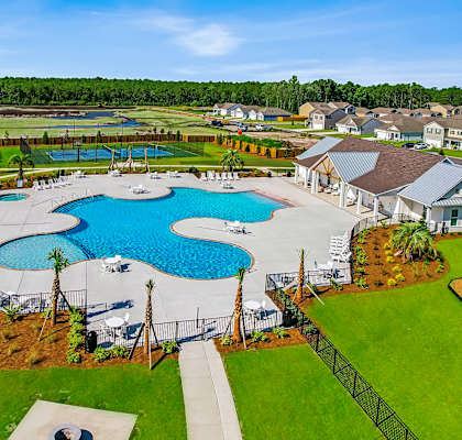 A large outdoor swimming pool surrounded by a fence and palm trees.