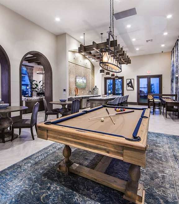 a pool table in a clubhouse with a bar and tables