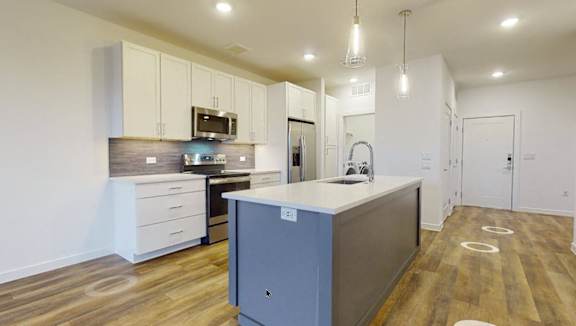 A modern kitchen with a large island and wooden flooring.