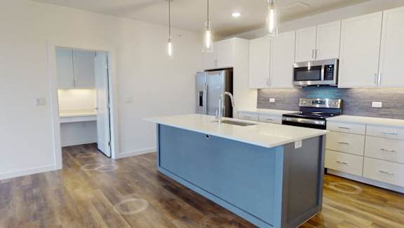 A modern kitchen with a central island and wooden flooring.