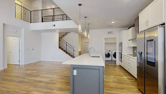 A modern kitchen with wooden floors and stainless steel appliances.