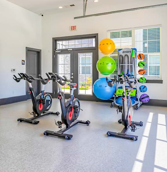 A gym with exercise equipment and a large mirror on the wall.
