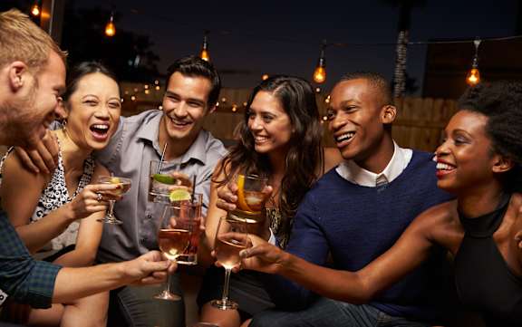 A group of people toasting with drinks at a bar at Premier at Cherry Hill, Cherry Hill
