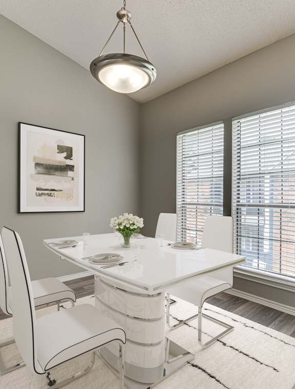 A dining room with a white table and chairs.