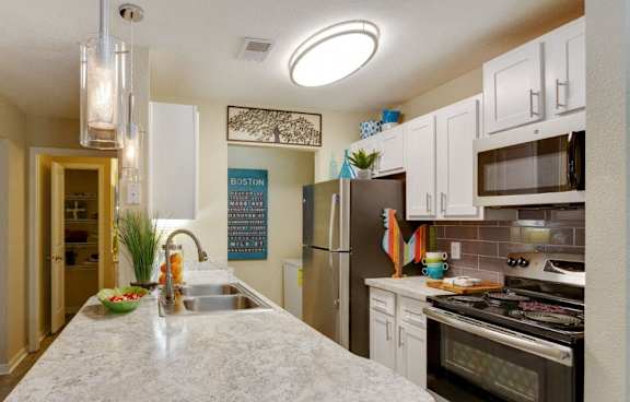 A kitchen with a marble countertop and stainless steel appliances.