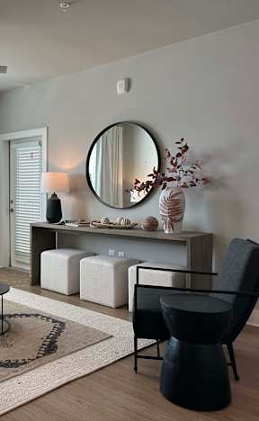 A living room with a black chair and a round mirror on the wall at The Beacon at 331 Apartments, Santa Rosa Beach, 32459