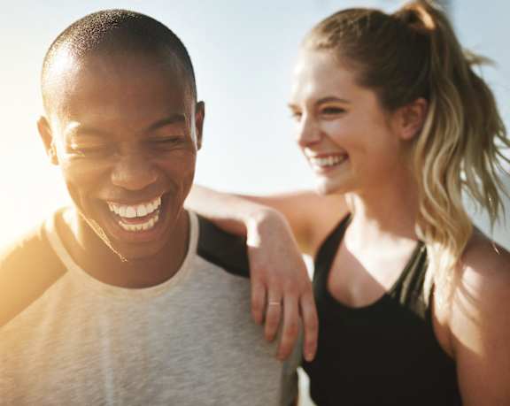 A man and a woman are standing close together, both smiling and enjoying each other's company.