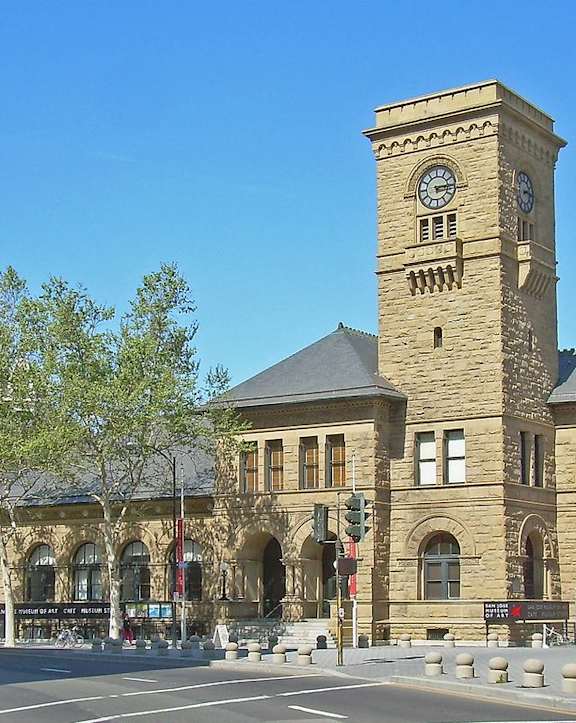 A large building with a clock tower in the middle of a city street.