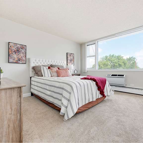 A bedroom with a bed, nightstand, and window.