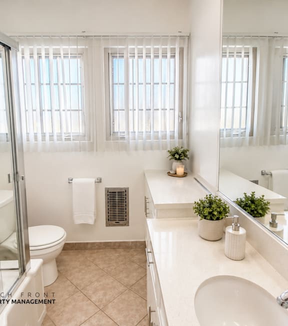 A bathroom with a toilet, sink, and mirror.