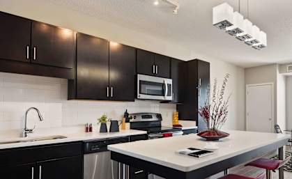 A modern kitchen with a white island and red bar stools.