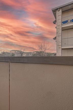 A balcony with a view of a sunset or sunrise. at Logan Ridge Apartments, Apartments, San Marcos, TX