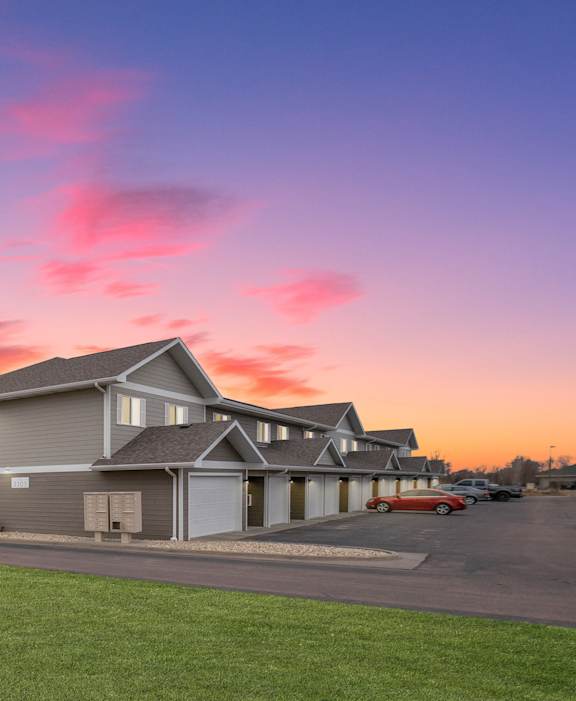 A building with a sign in front of it and a sunset in the background.