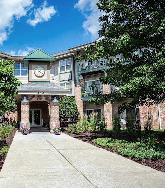 a sidewalk in front of a brick building with a clock on the front