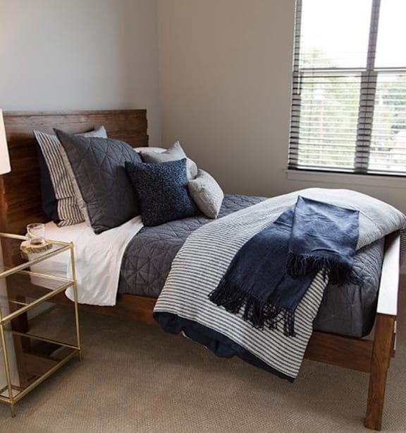 A bed with a blue and white striped blanket and pillows.