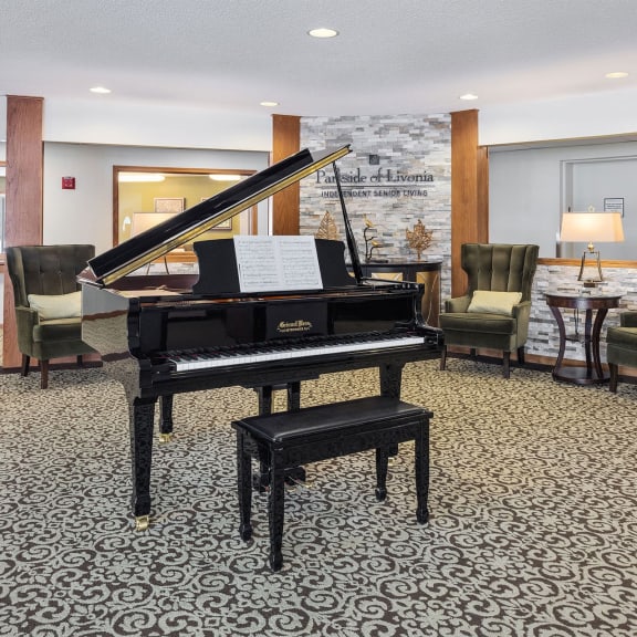 a piano in a lobby with chairs and a table
