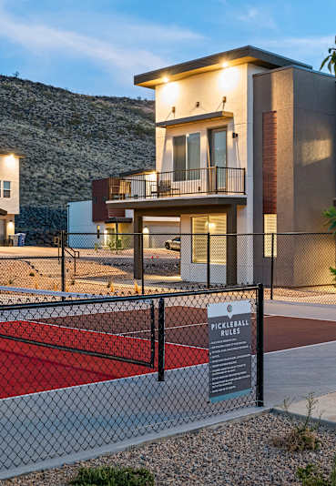 A pickleball court is located in front of a modern apartment complex.