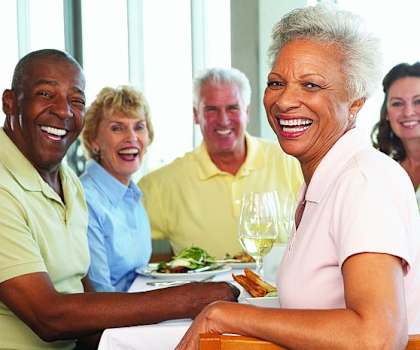 a group of people sitting at a table with food and wine