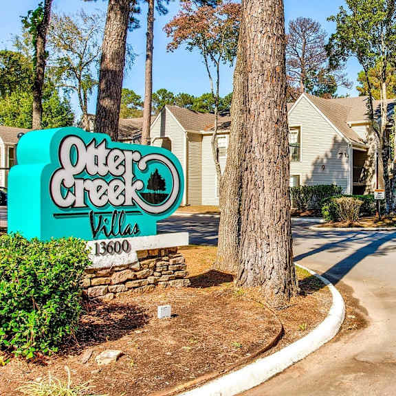 A sign for Outer Creek Villas stands in front of a row of houses.
