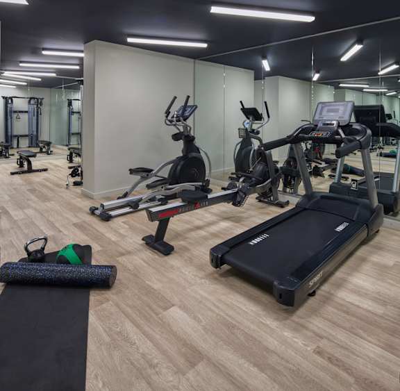 A gym with a variety of equipment including treadmills, stationary bikes, and weight machines.