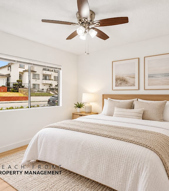 A spacious room with wooden flooring and a large window with blinds.