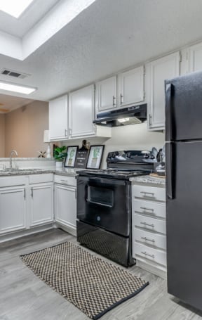 a kitchen with white cabinets and black appliances
