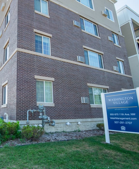 a brick apartment building with a sign in front of it