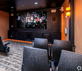 A row of black chairs are arranged in front of a screen.