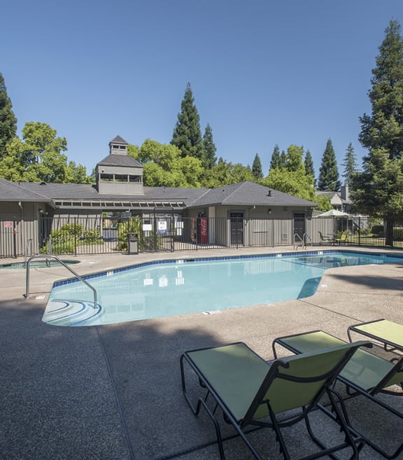 Pepperwood apartments swimming pool and pool deck lounge chairs, tables, and sun umbrellas