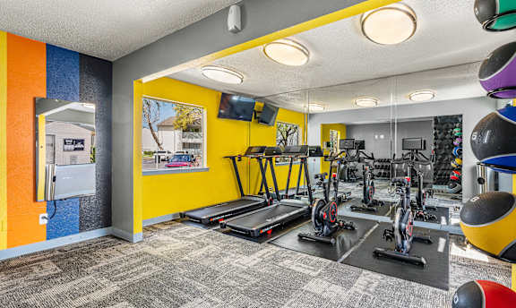A gym with a variety of equipment including treadmills, exercise bikes, and weight machines.