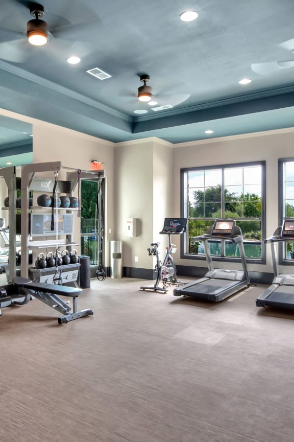 a large fitness room with cardio equipment and windows